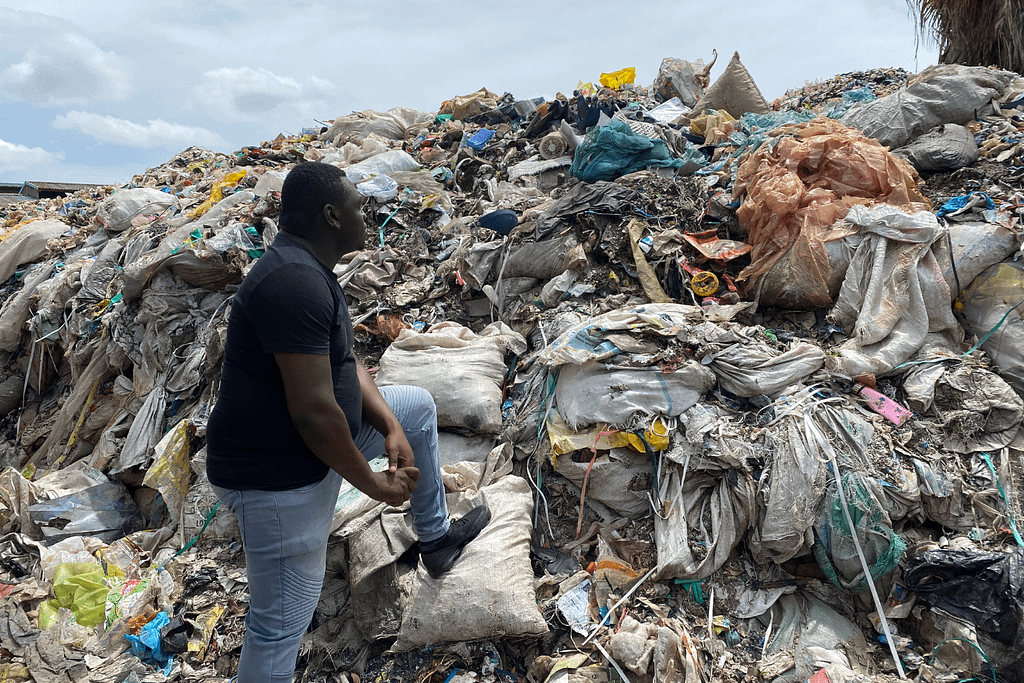 man standing next to a plastic landfill